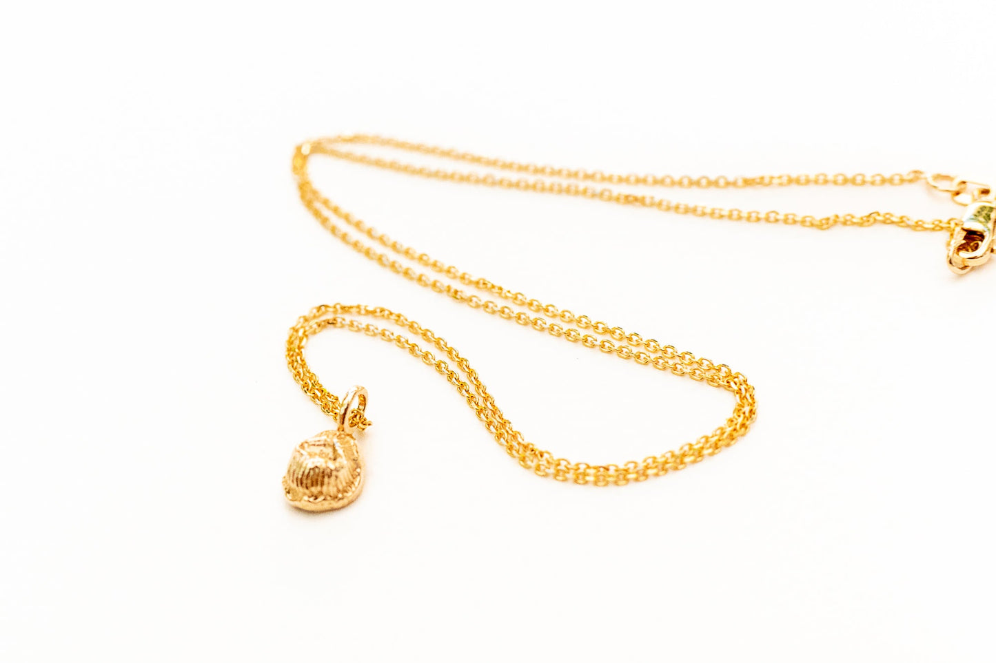 Tiny coral polyp pendant catching light on delicate chain