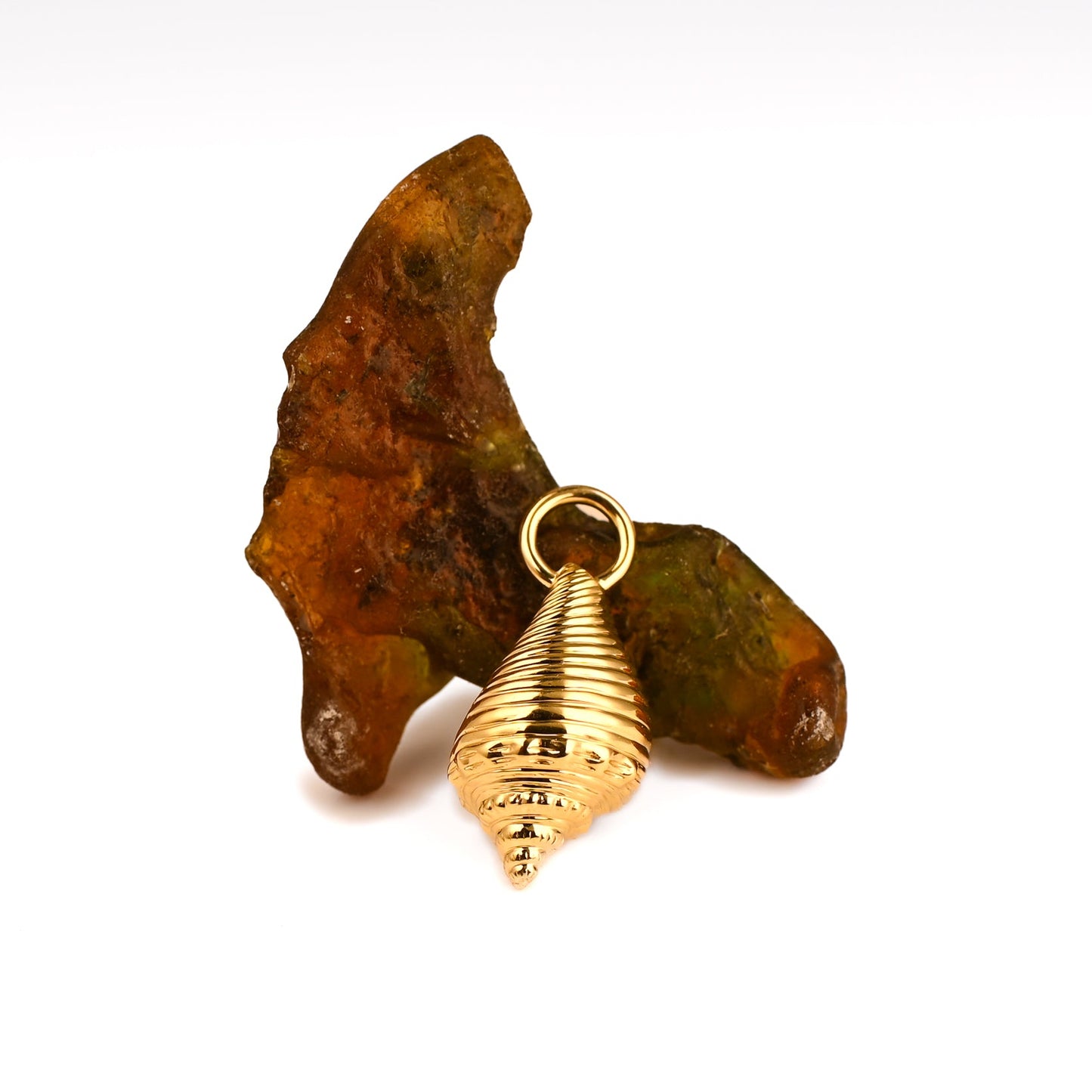 gold conch shell pendant resting on sea glass