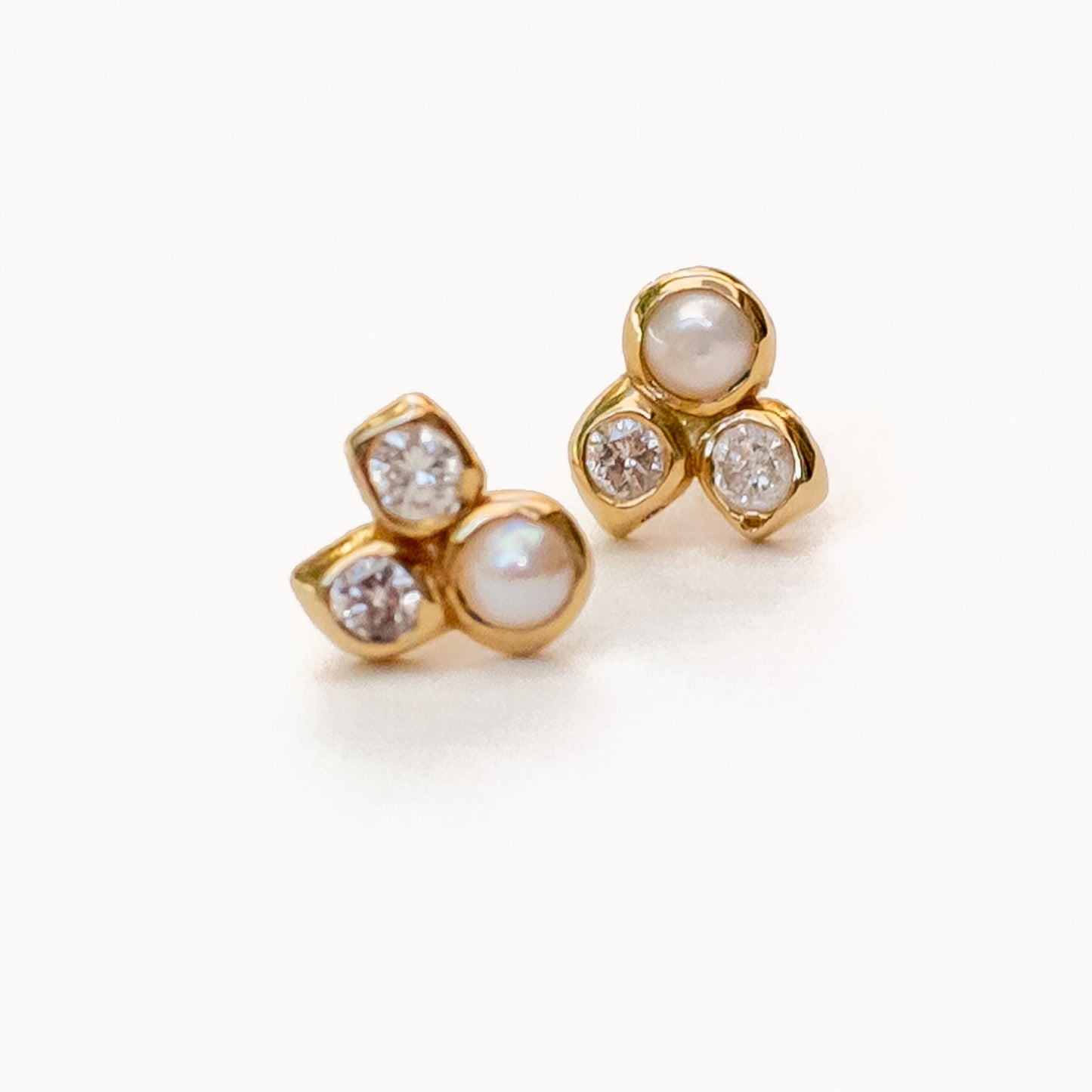 Overhead view of 18K gold harmonia studs with pearl and diamond gemstones