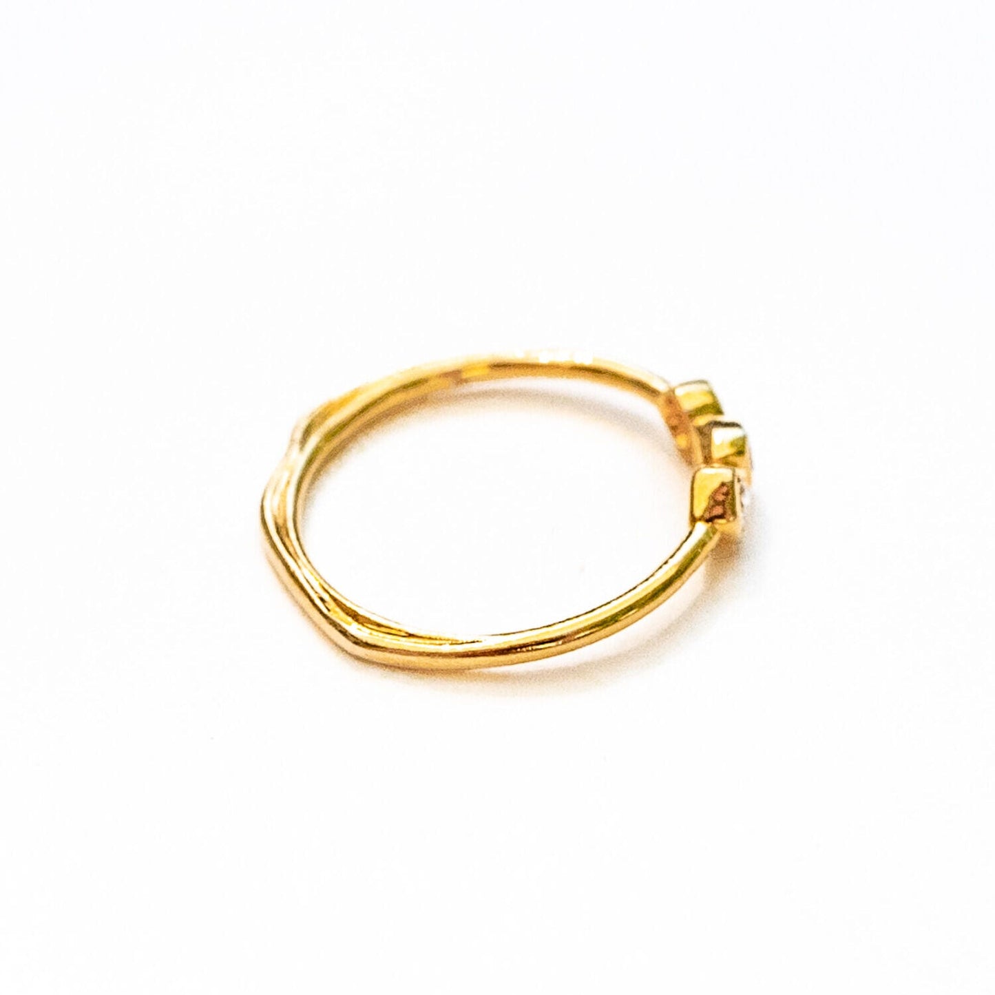 Side profile of 18K gold three diamond ring showing sculptural band design