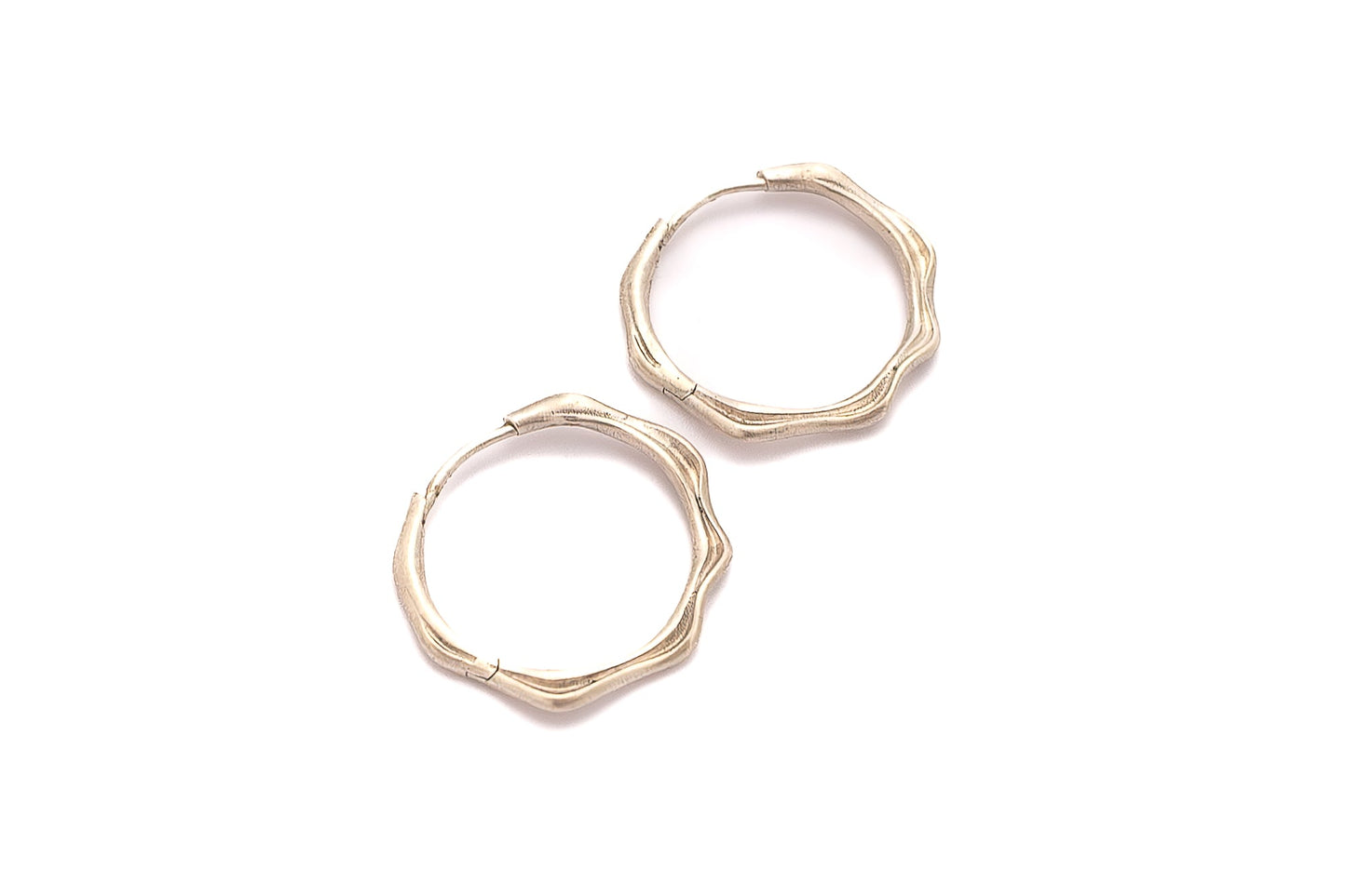 Close-up of silver waterline earrings showing flowing lines and satin finish