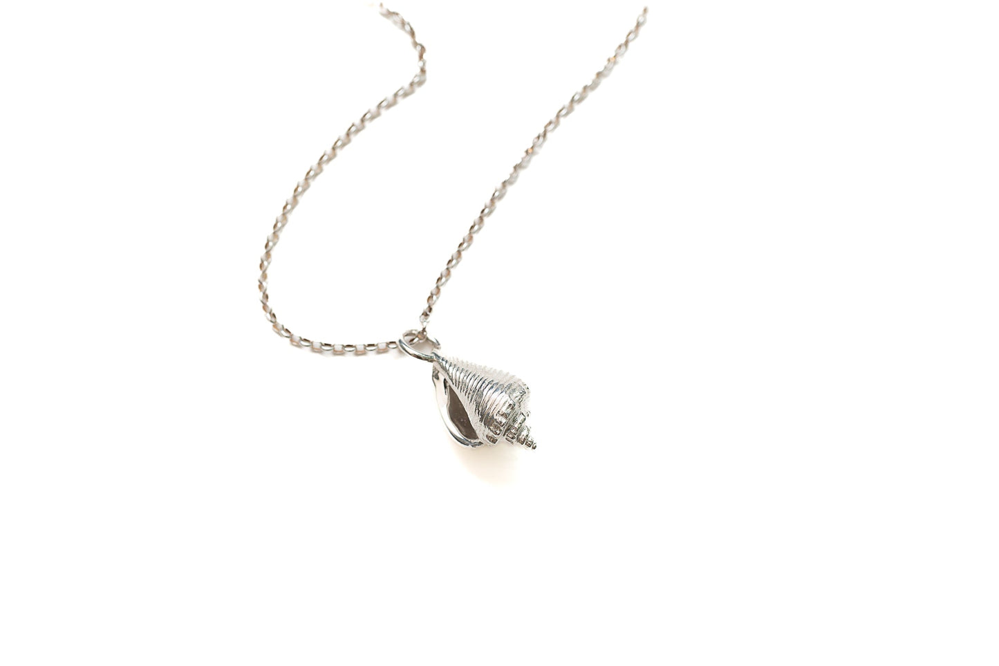 Close-up of sculptural sterling silver conch pendant with organic shell detail