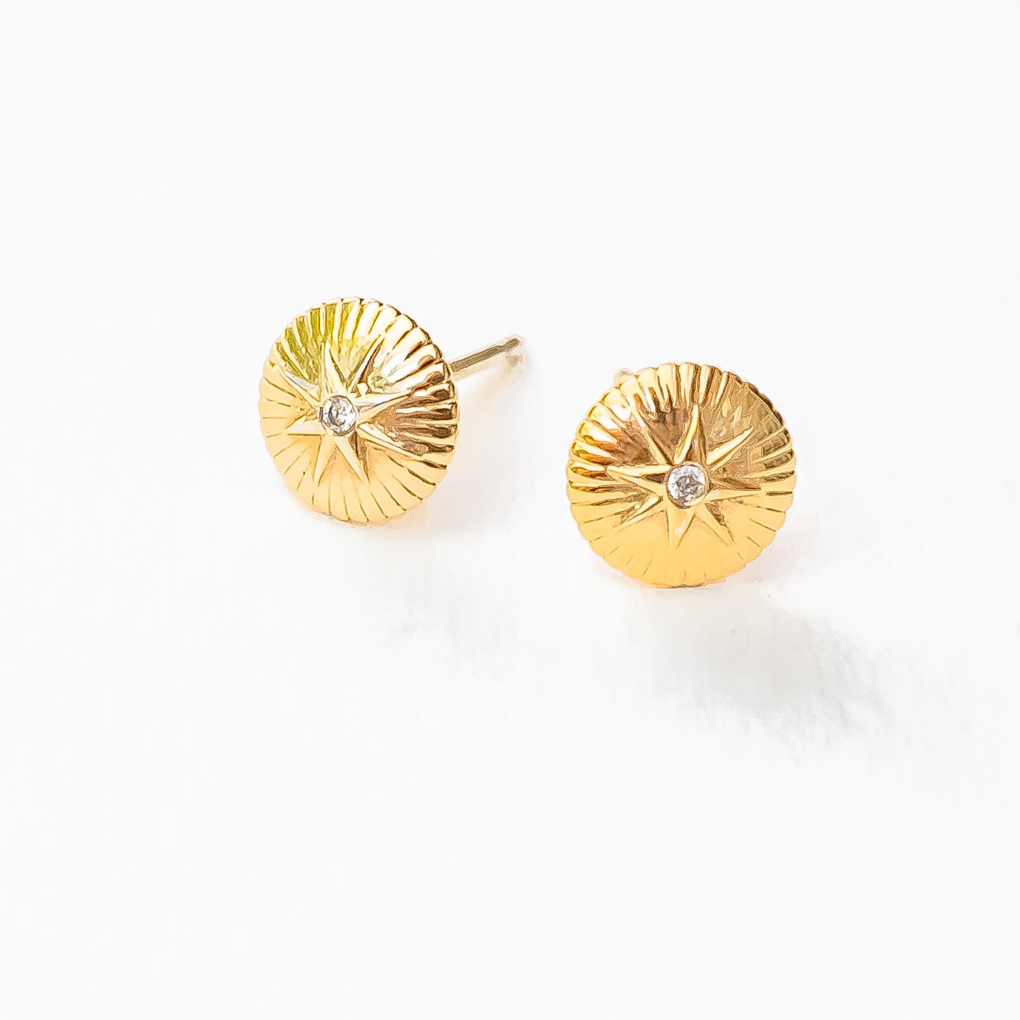Hand detail showing 18K gold nova diamond studs catching light