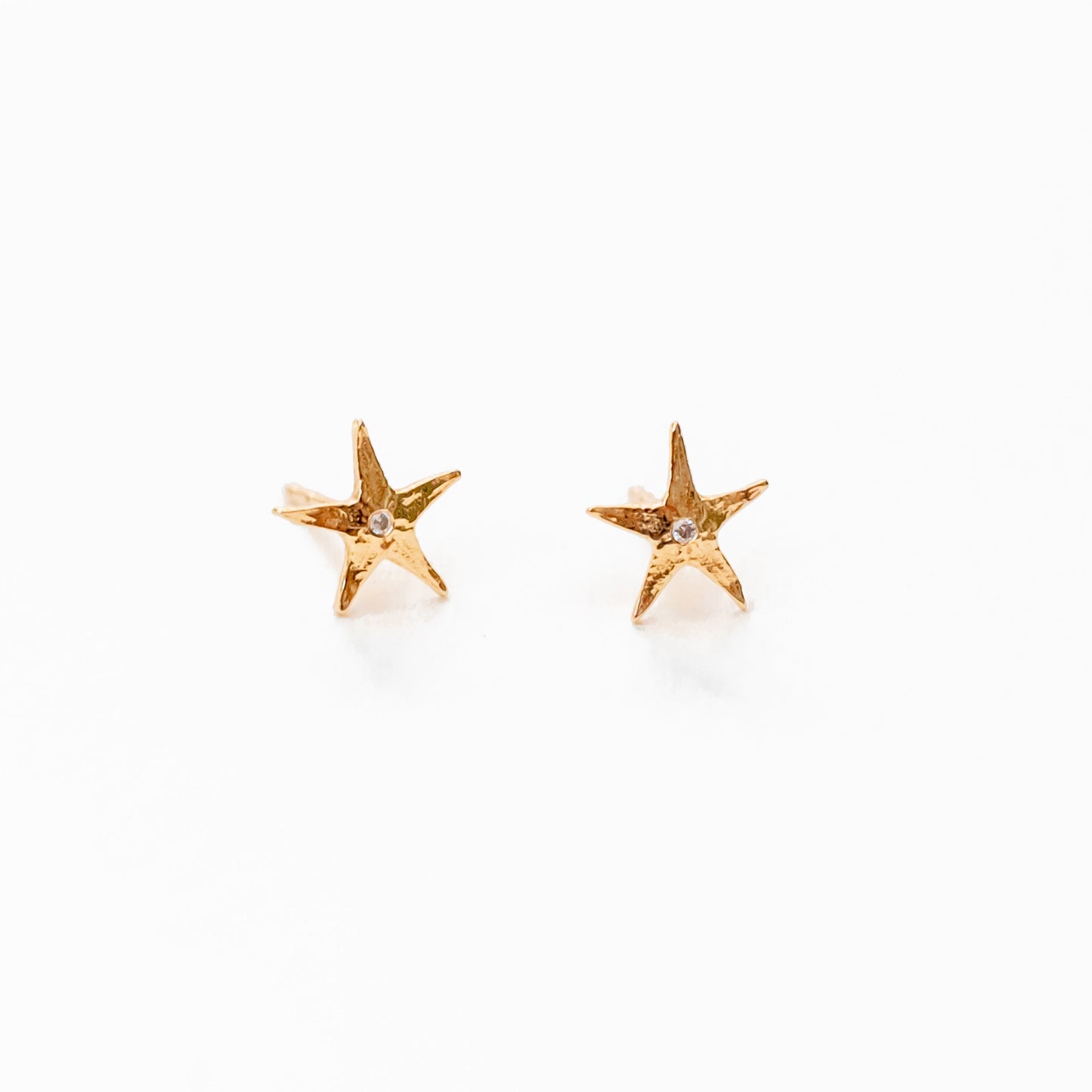 Model wearing 14K gold sea star diamond studs with ocean connection aesthetic